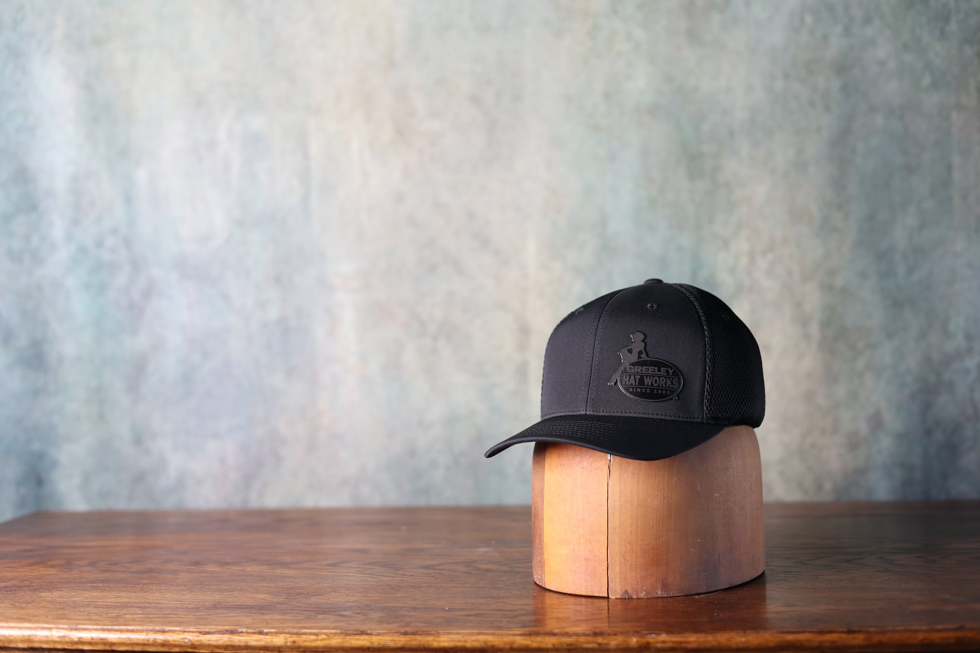 Photo of the black leather patch baseball hat from Greeley Hat Works with the logo in black on black