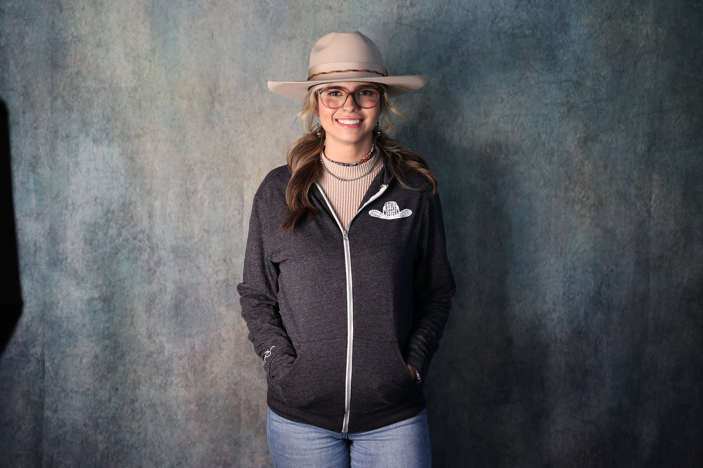 Photo of woman wearing grey Still Western Zip-up Hoodie from Greeley Hat works