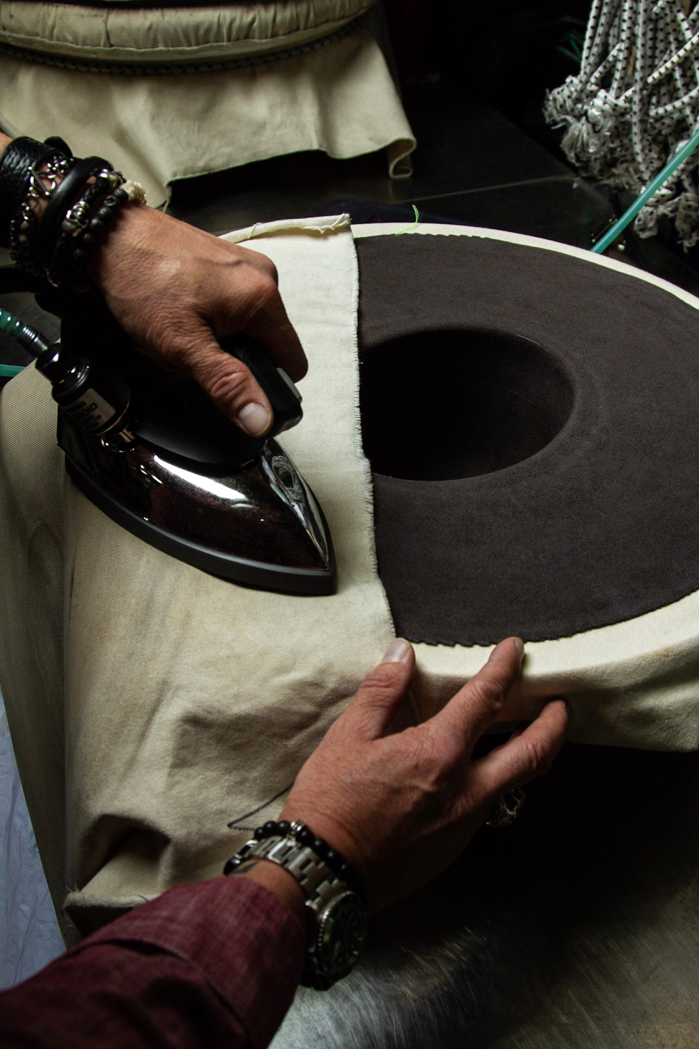 Photo of hatmaker at Greeley Hat Works in Greeley, Colorado putting the finishing touches on a custom western hat for a customer