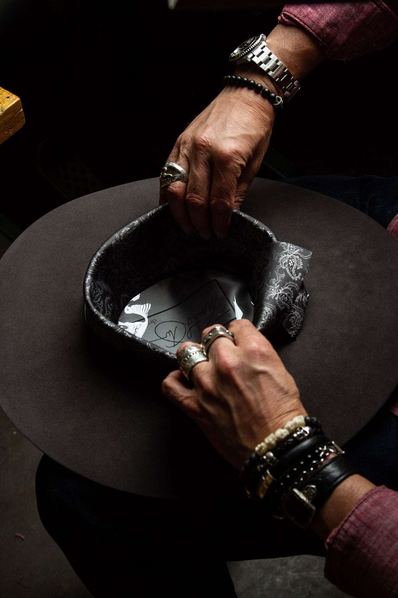 Photo of hatmaker at Greeley Hat Works in Greeley, Colorado inserting a custom sweatband in a custom western hat for a customer