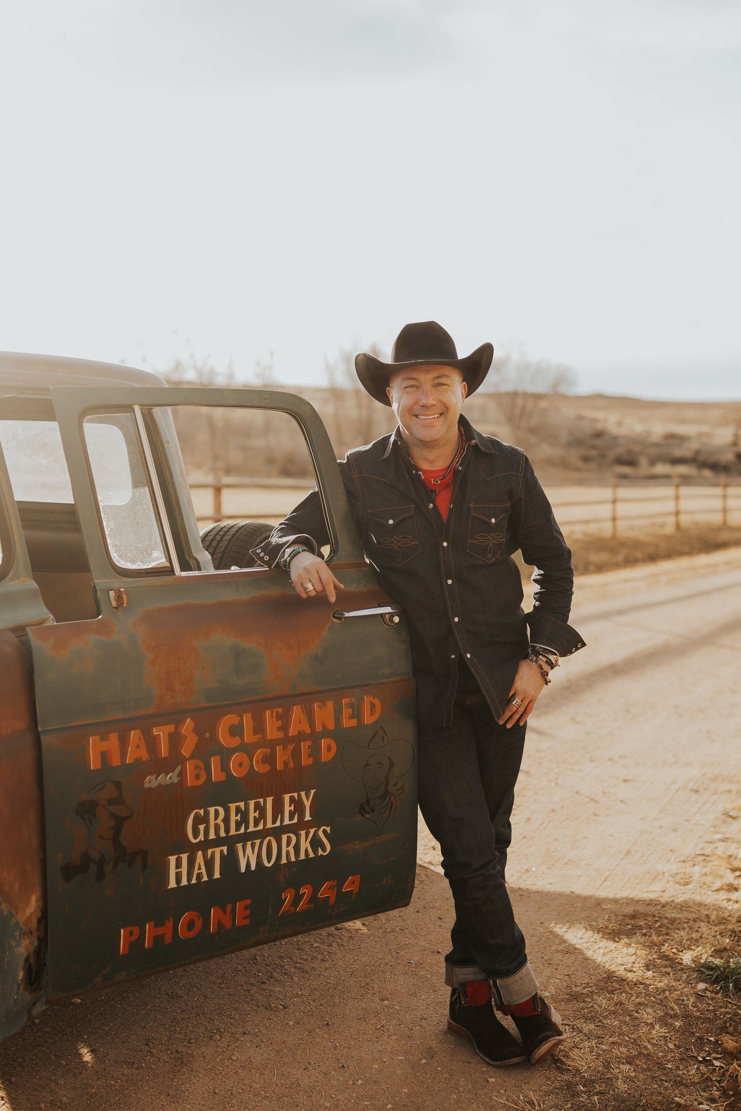 Greeley Hat Works Owner and C.reative V.ision O.fficer Trent Johnson leans on rustic Greeley Hat Works truck.