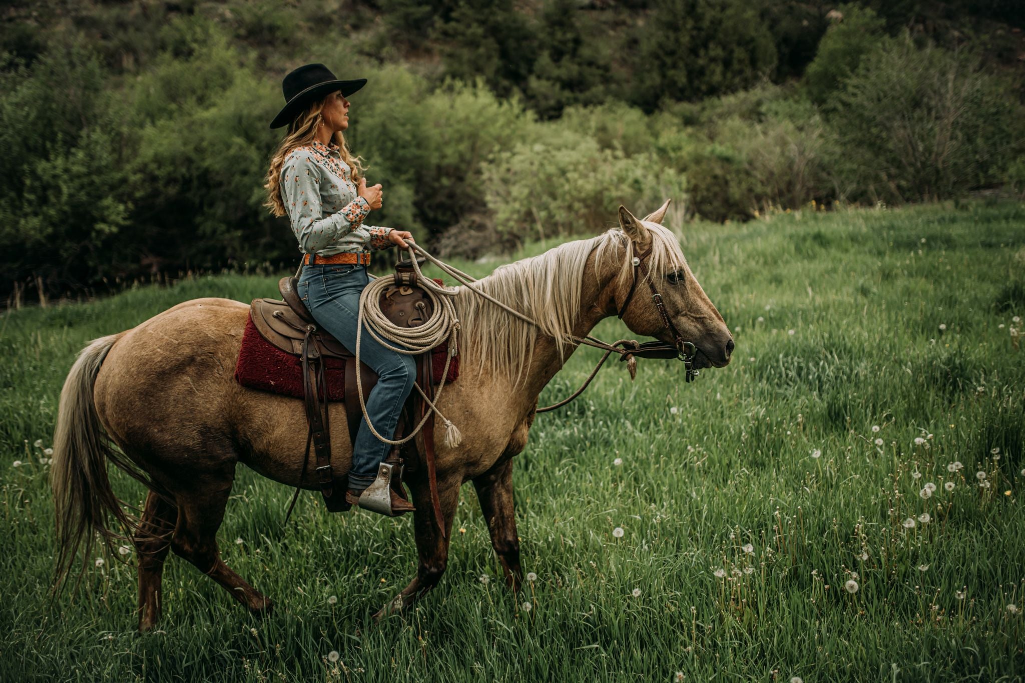 Photo of cowgirl wearing custom cowboy hat from Greeley Hat Works while riding her horse in the wilderness