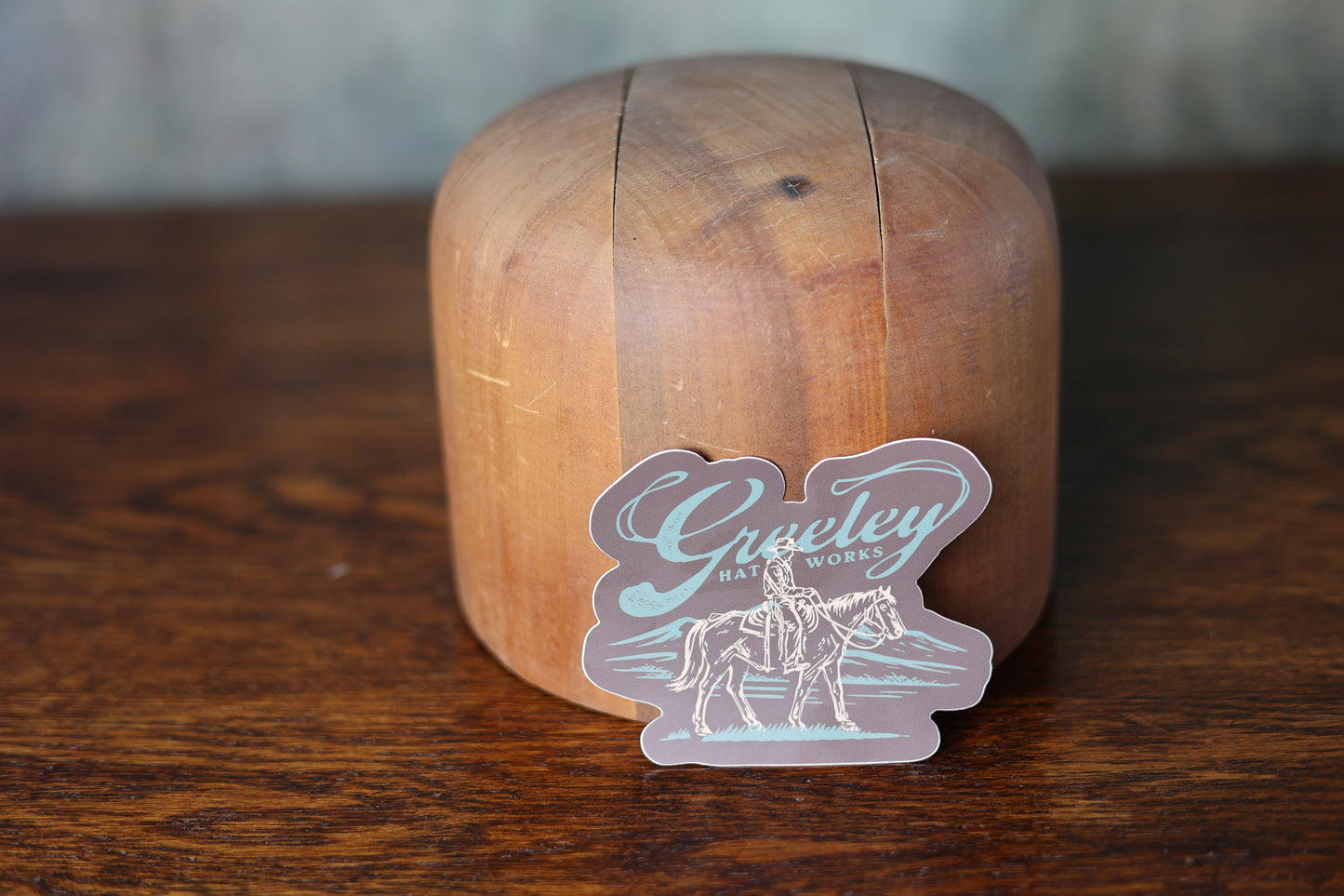 Photo of a GHW x Bria Sticker featuring a cowboy and mountains leaning on a cowboy hat mold