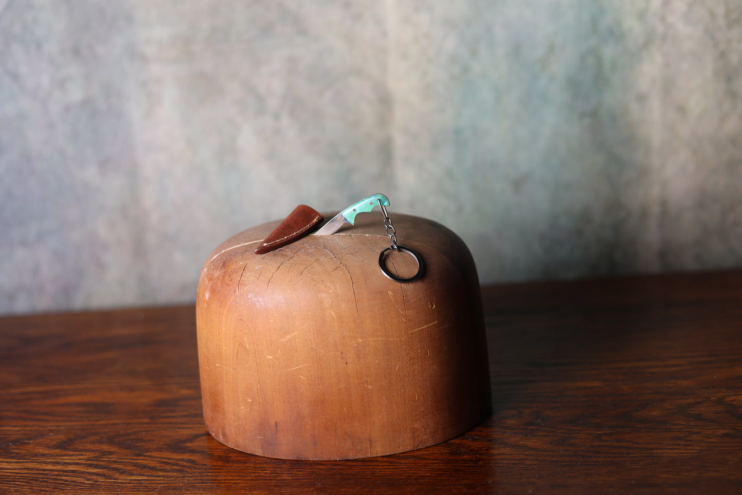 Photo of a mini 9 Lazy 3 Knive with a teal handle in a wooden hat mold