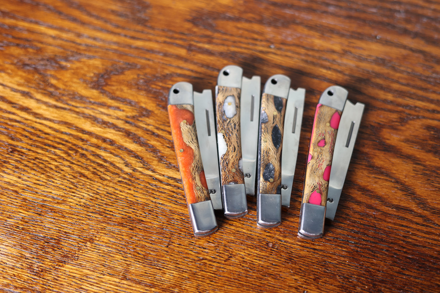 Photo showing four unique 9 Lazy 3 Knives and their handles on a wooden background