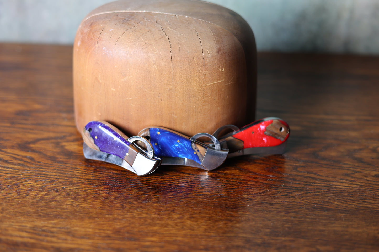 Photo of three bright 9 Lazy 3 Knives against a wooden hat mold