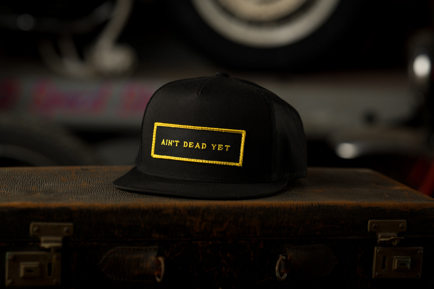 Photo of black Ain’t Dead Yet Cap from Greeley Hat Works on antique trunk