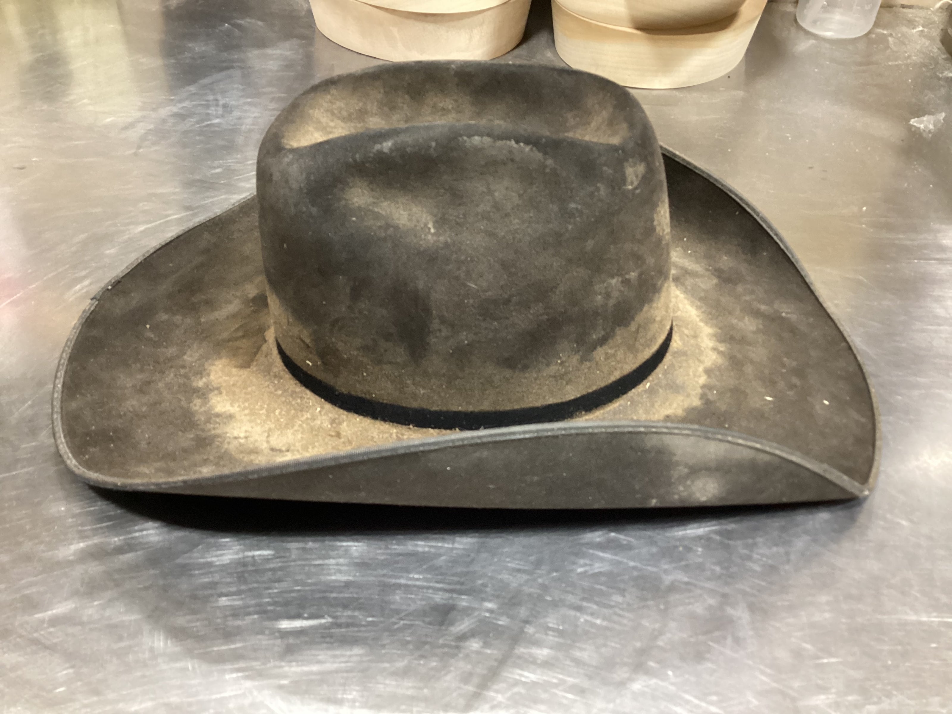 Side photo of dirty cream-colored cowboy hat prior to ReCraft services from Greeley Hat Works